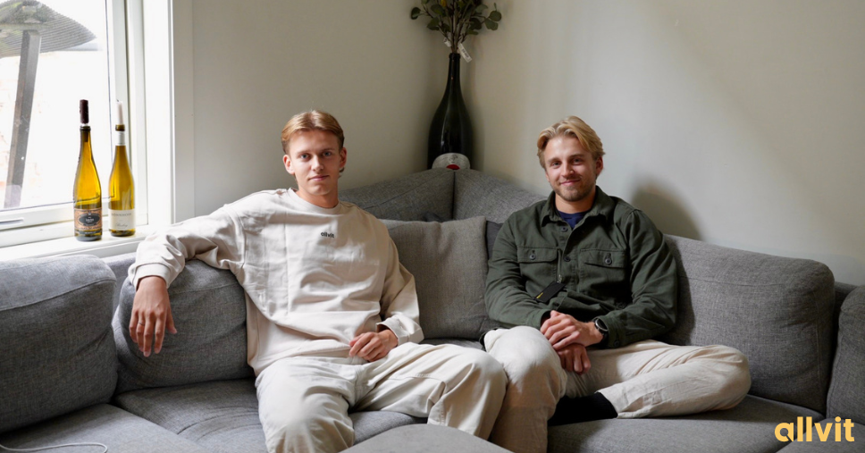 To gutter som sitter sammen i en sofa i kollektivet sitt. Foto.