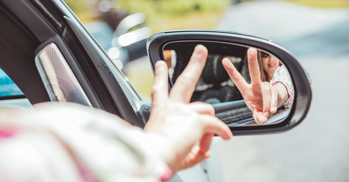 To fingre som holdes opp foran et bilspeil. 