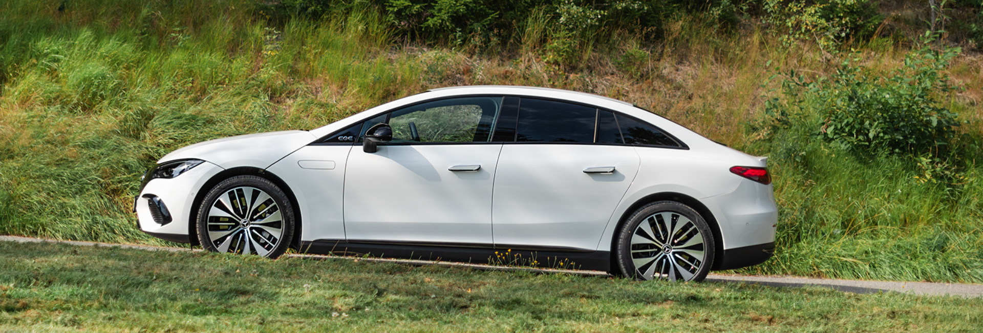 Hvit Mercedes EQE 300 i fart, sett fra siden.