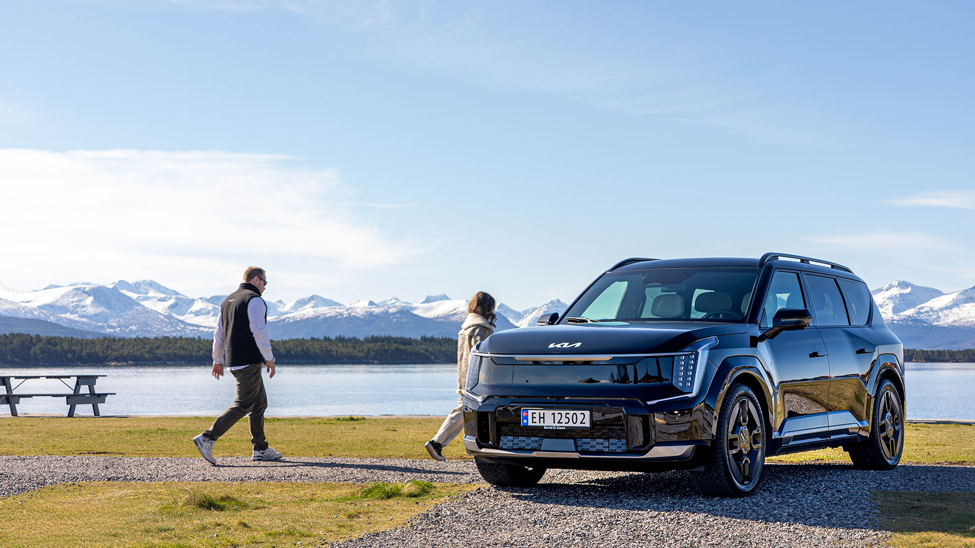 Kia EV9 i svart metallic med sjø og fjell i bakgrunnen.