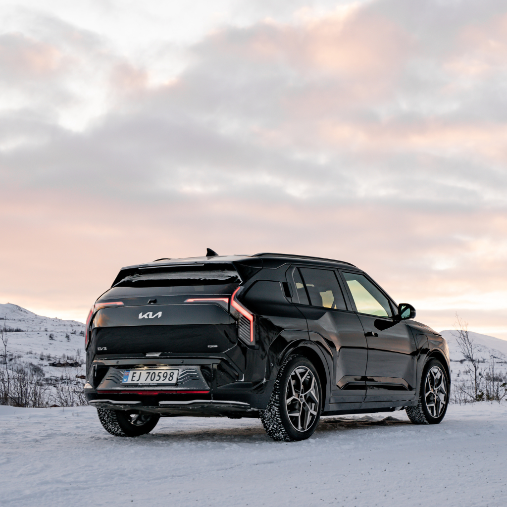 Svart Kia EV3 sett bakfra i solnedgang på vinteren
