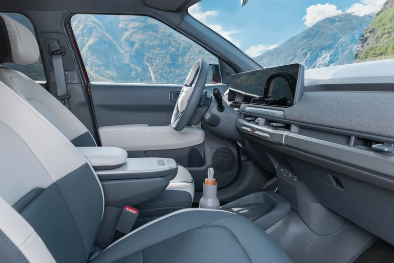 Førermiljø og interiør i Kia Ev3 sett fra siden og passasjersete