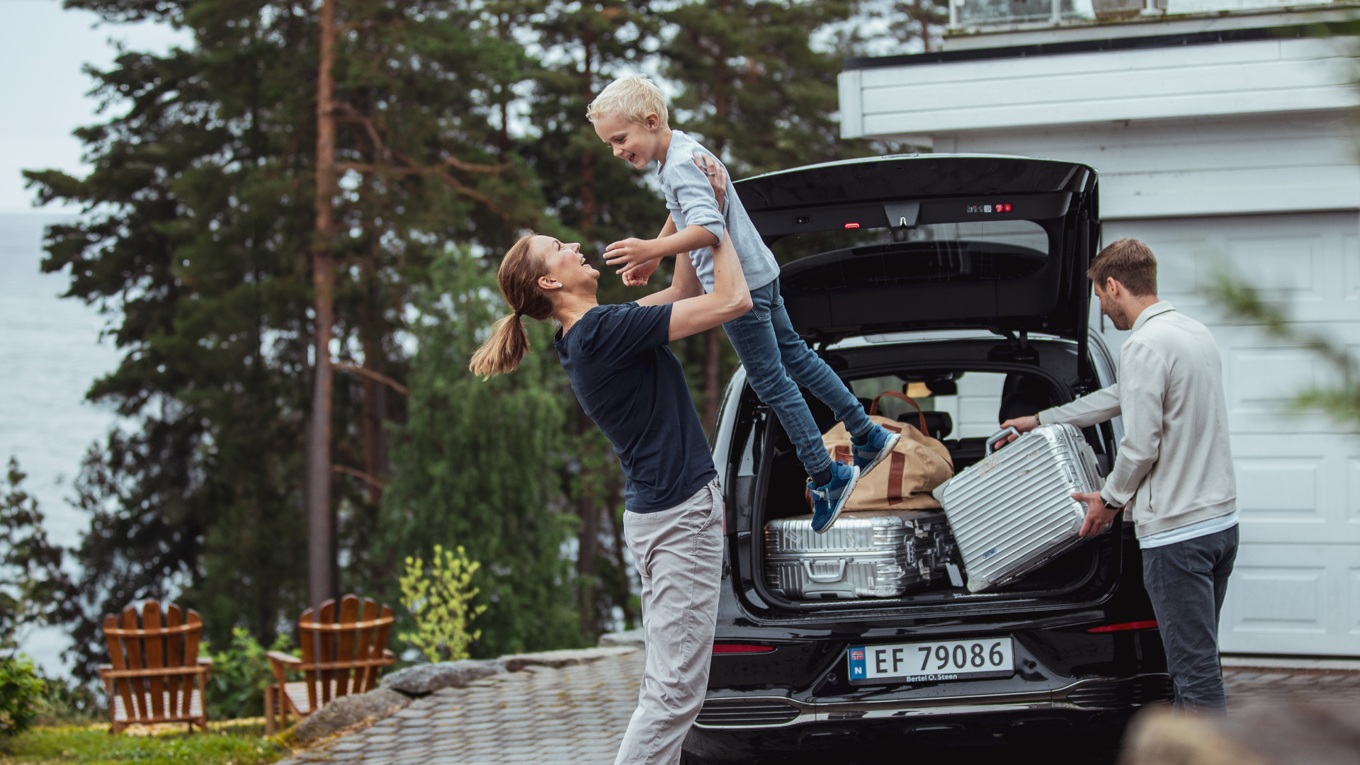 Familie som pakker bagasje inn i bilen sin