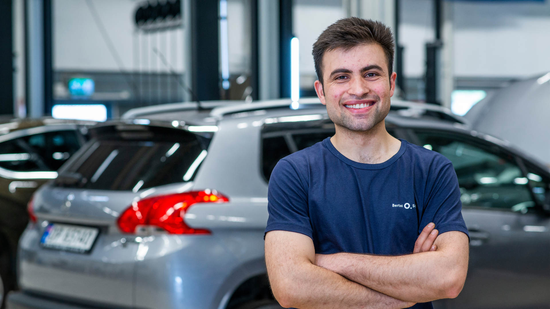 Mekaniker som smiler foran en Mercedes-Benz på verksted