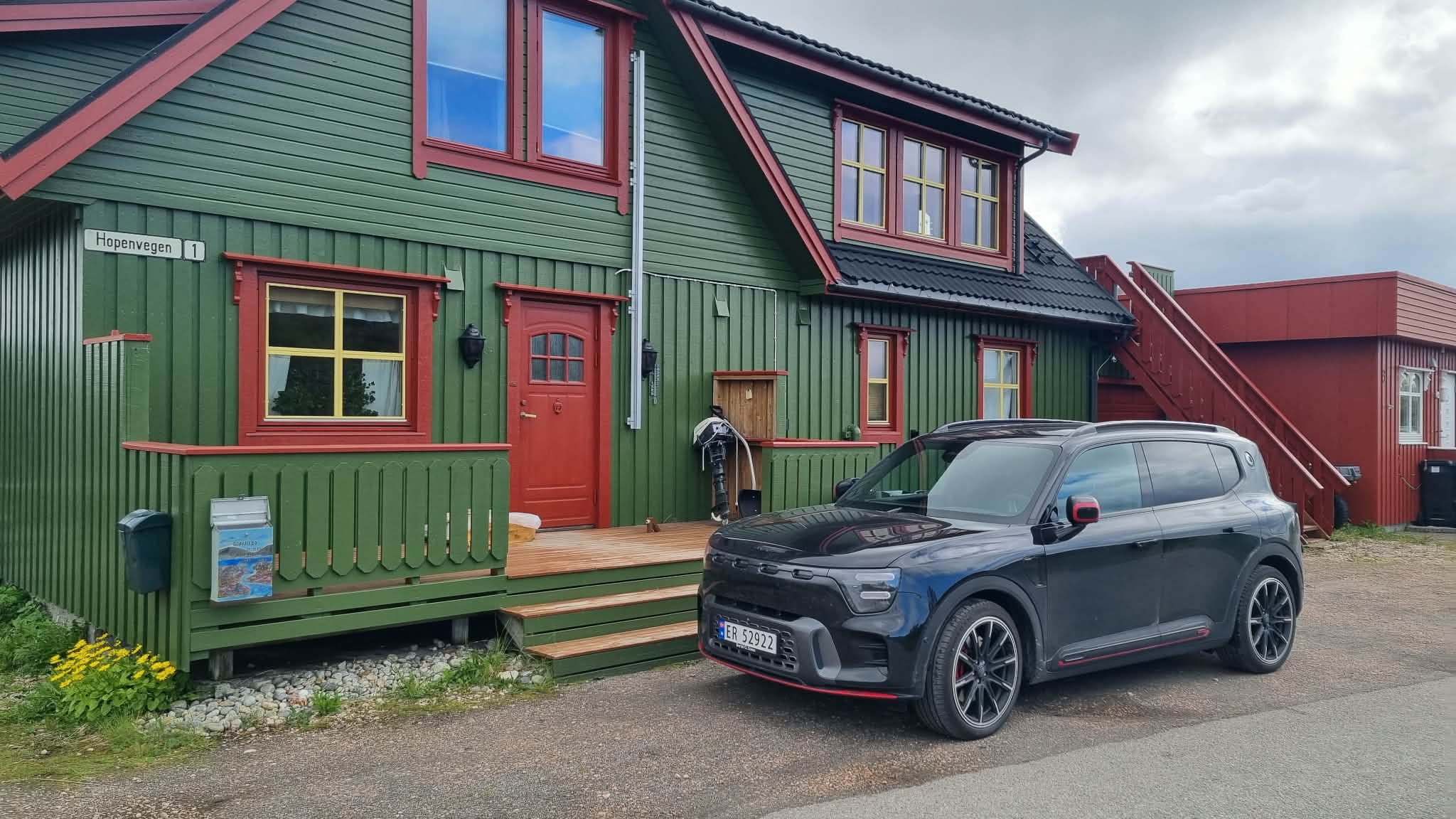 Sort smart #5 BRABUS parkert foran et grønt trehus