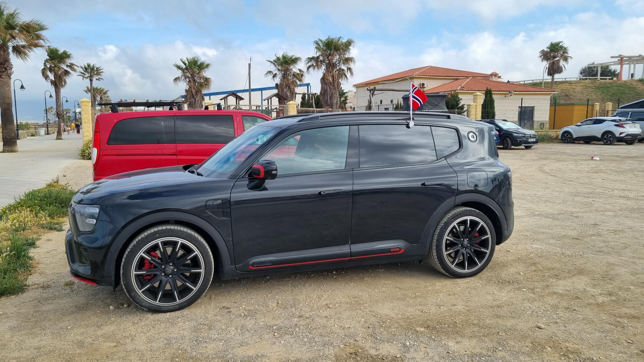 Sort smart #5 BRABUS parkert ved en strandpromenade med norsk flagg på taket
