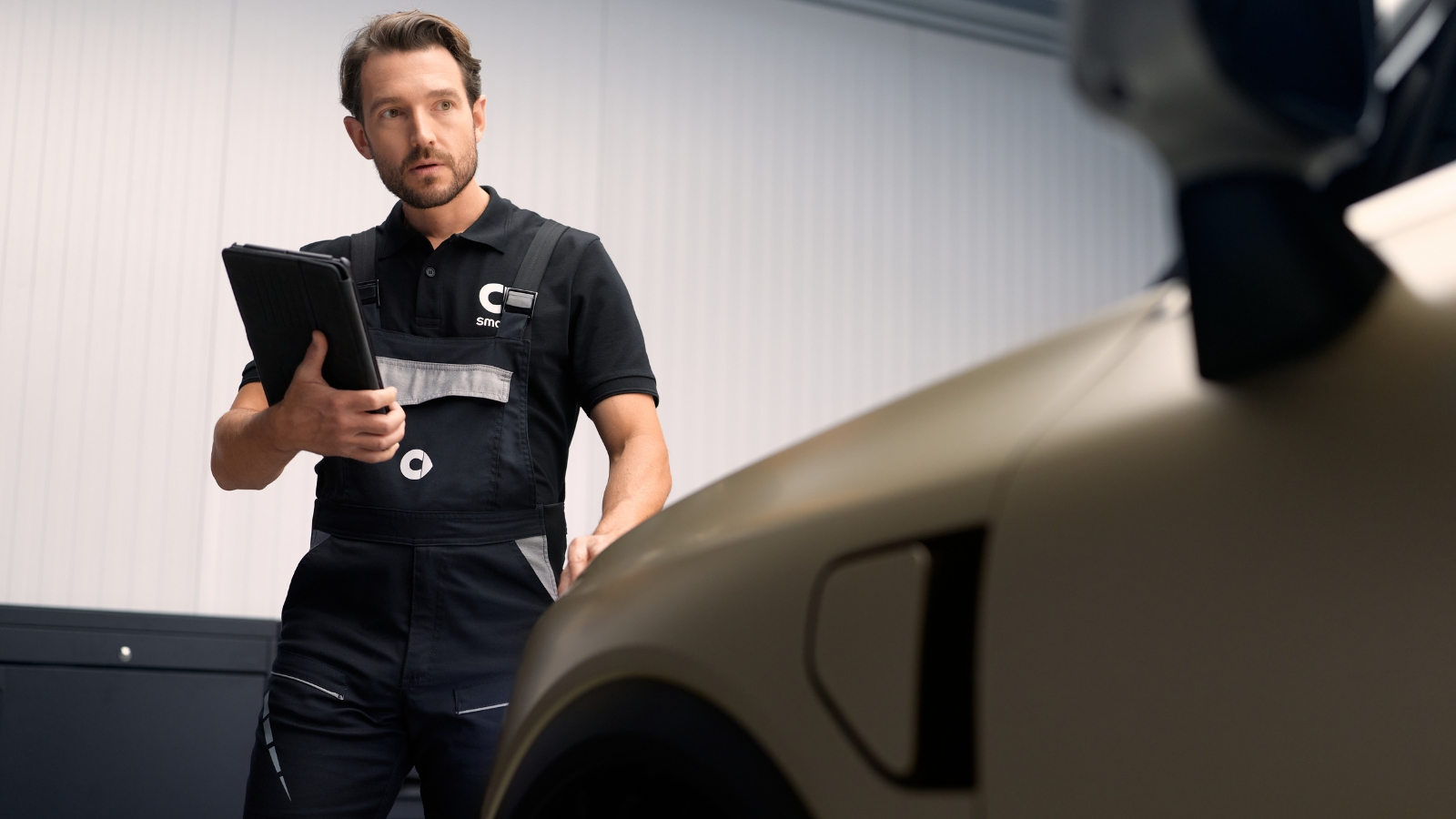 smart-servicetekniker med nettbrett inspiserer en bil på verksted
