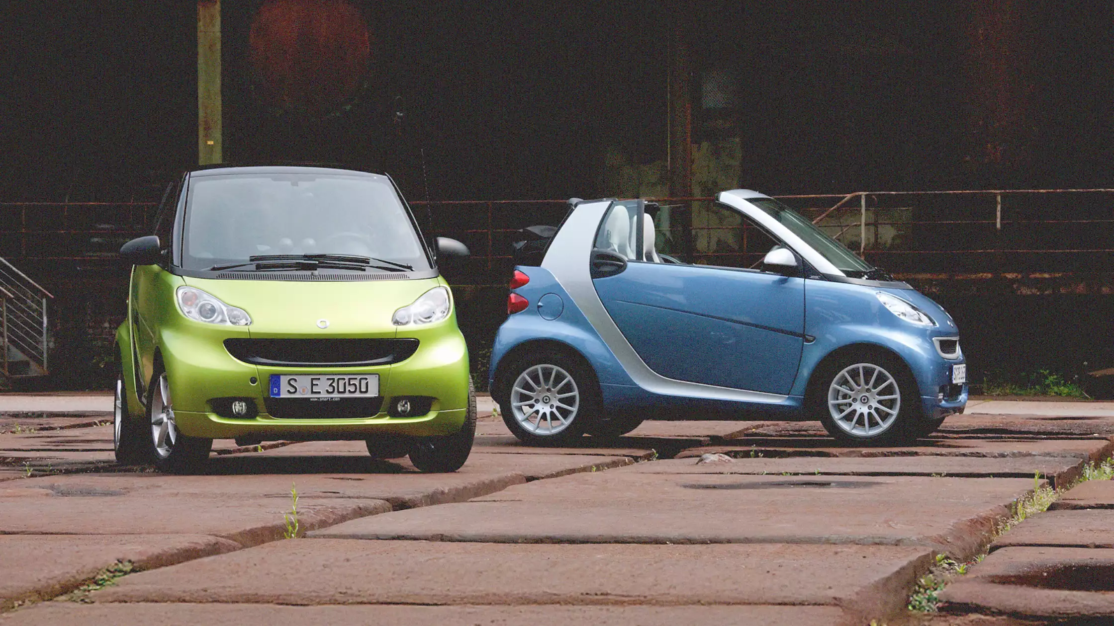 Grønn smart fortwo og blå smart fortwo cabrio parkert i urbant miljø