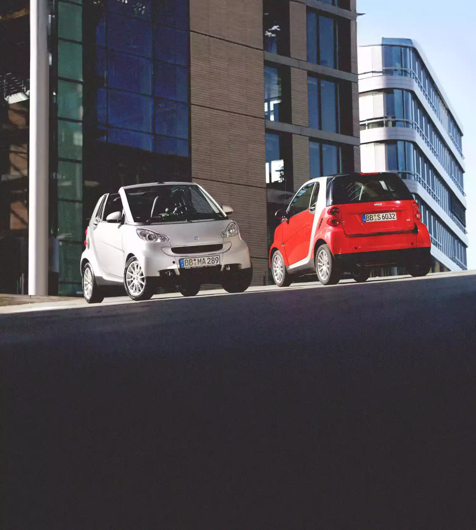 To klassiske smart fortwo-modeller utenfor en moderne bygning