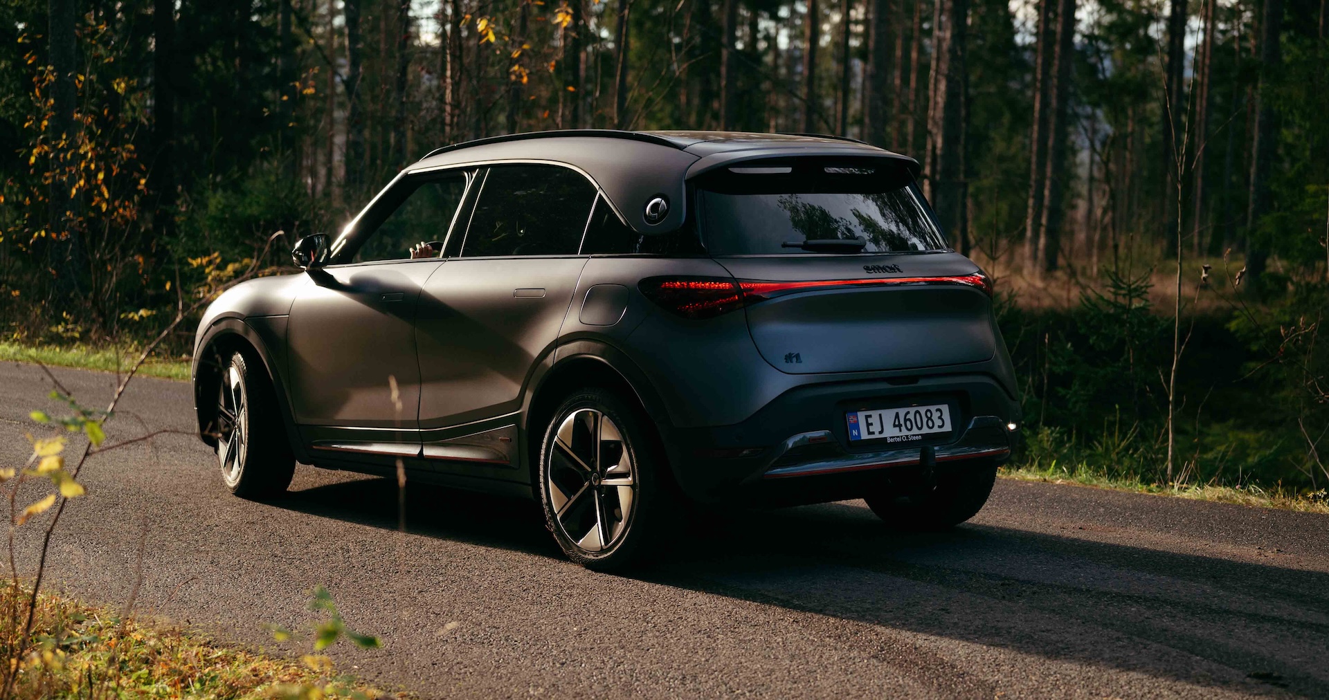 smart #1 på landevei omgitt av skog