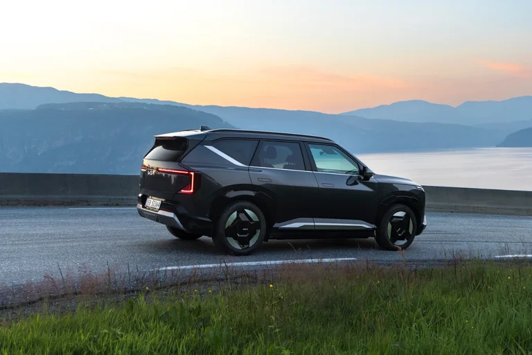 Kia EV5 i svart metallic sett fra siden i soldnedgang i norsk landskap