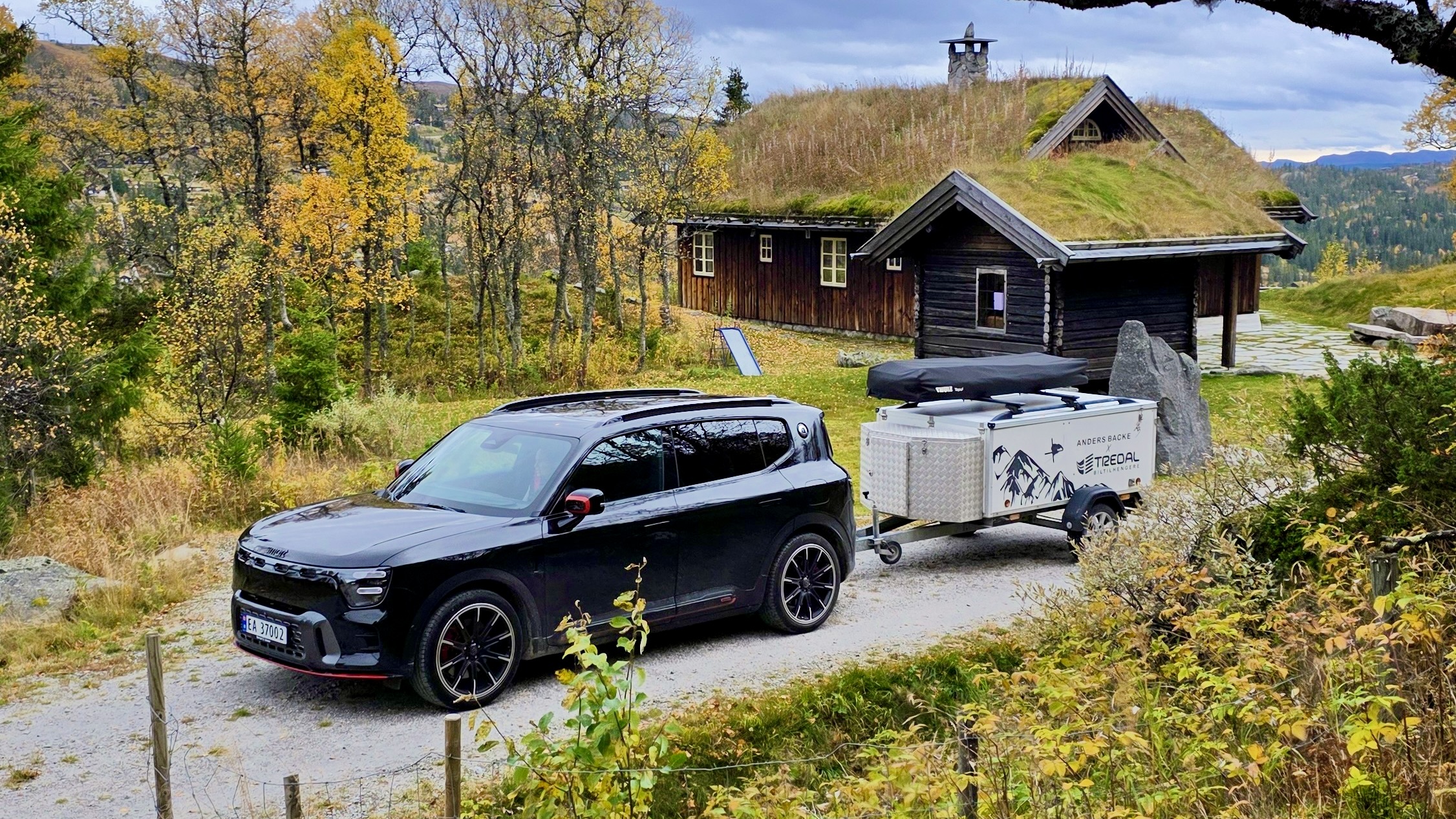 Svart smart #5 BRABUS med tilhenger foran en hytte i naturskjønne omgivelser