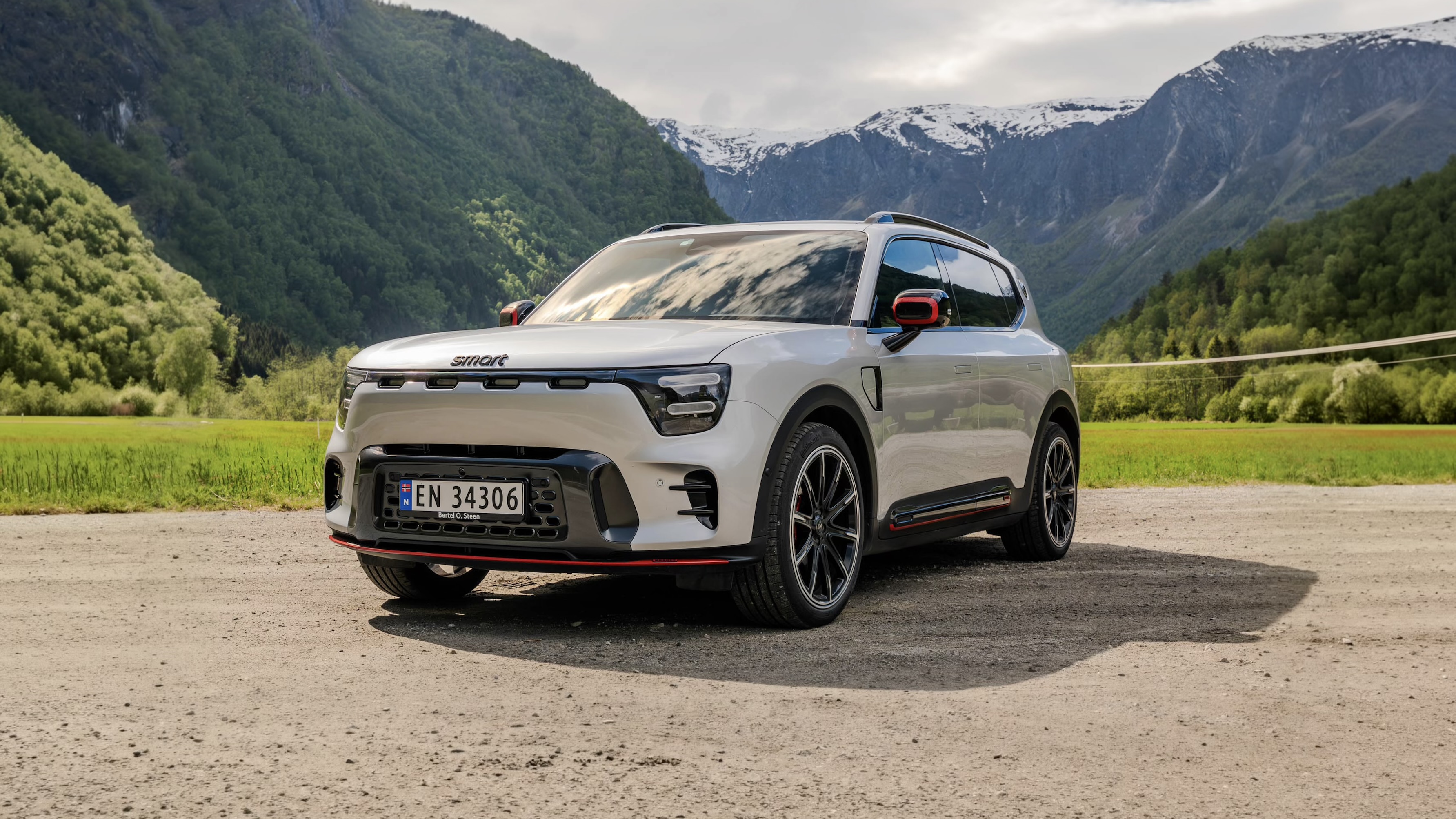 Sølvfarget smart #5 BRABUS sett skrått forfra med fjellandskap i bakgrunnen