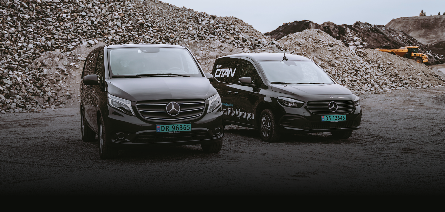 To Mercedes varebiler på et grustak, oppstilt ved siden av hverandre.
