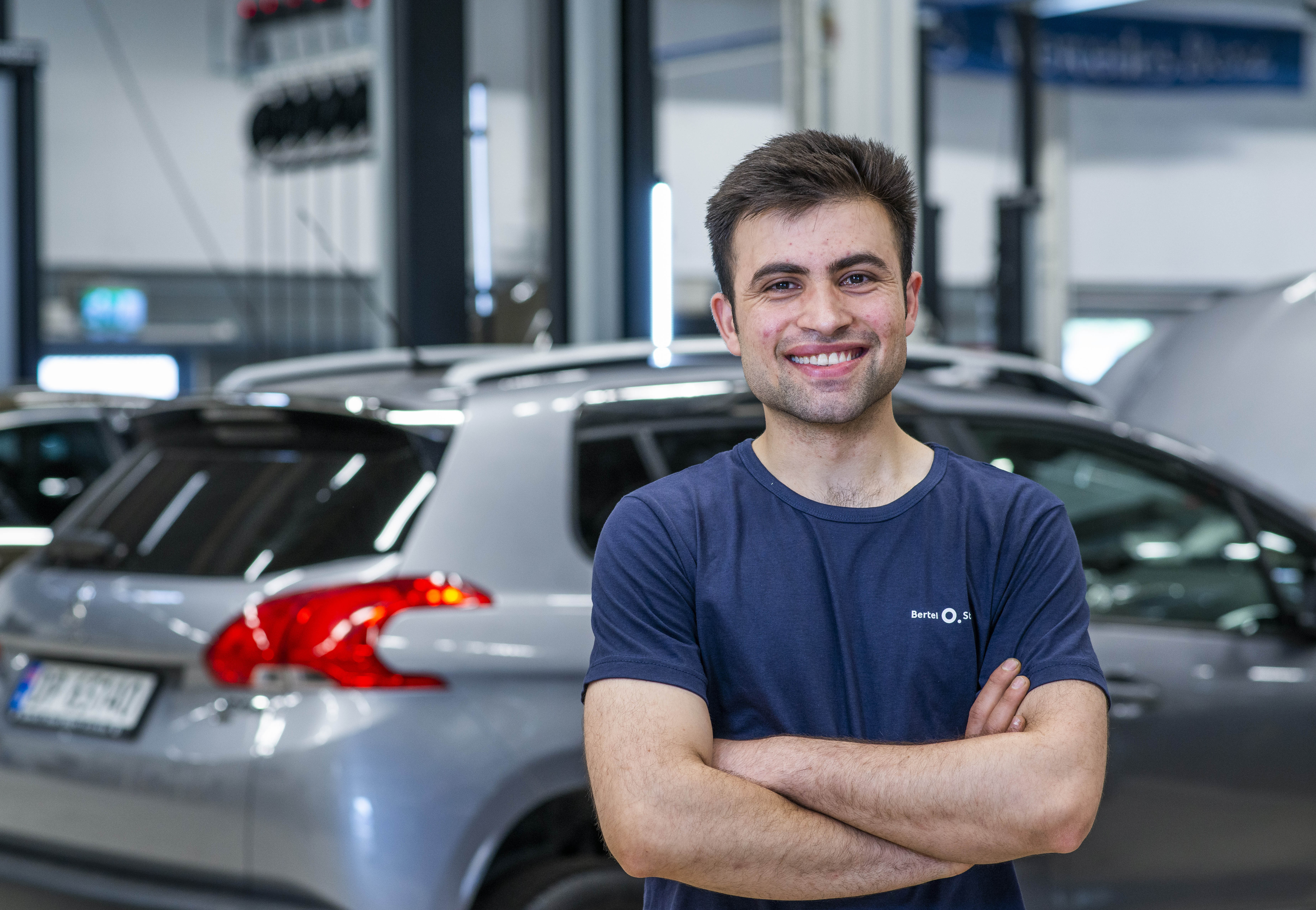 Mekaniker hos Bertel O. Steen står på verkstedet og smiler til kamera.