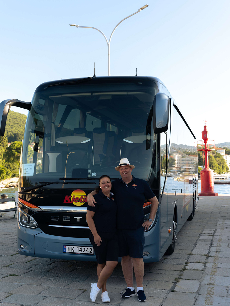 Bilde av mann og kvinne foran en buss