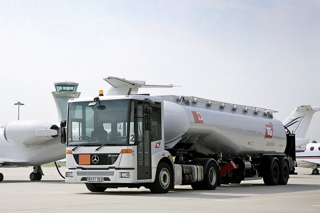 Mrecedes-Benz Econic parkert på flystripe foran to fly