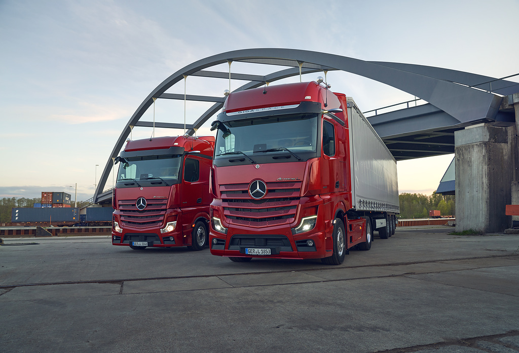 To røde Mercedes-Benz Actros L oppstilt foran bro