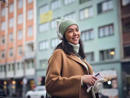 Kvinne i bybilde som hører på lydbok på gåturen