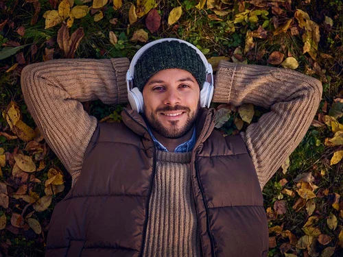 Lytting til lydbok med hodetelefoner i høstløvet