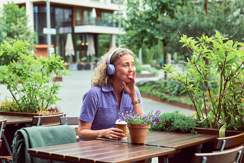 Lytting til lydbok med hodetelefoner på ute på kafé