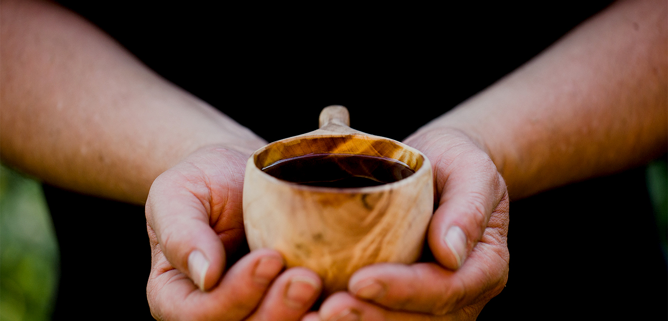 Man holding wooden mug with coffee