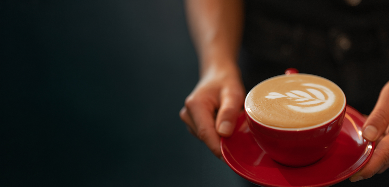 Girl holding a cup of coffee showing latte art
