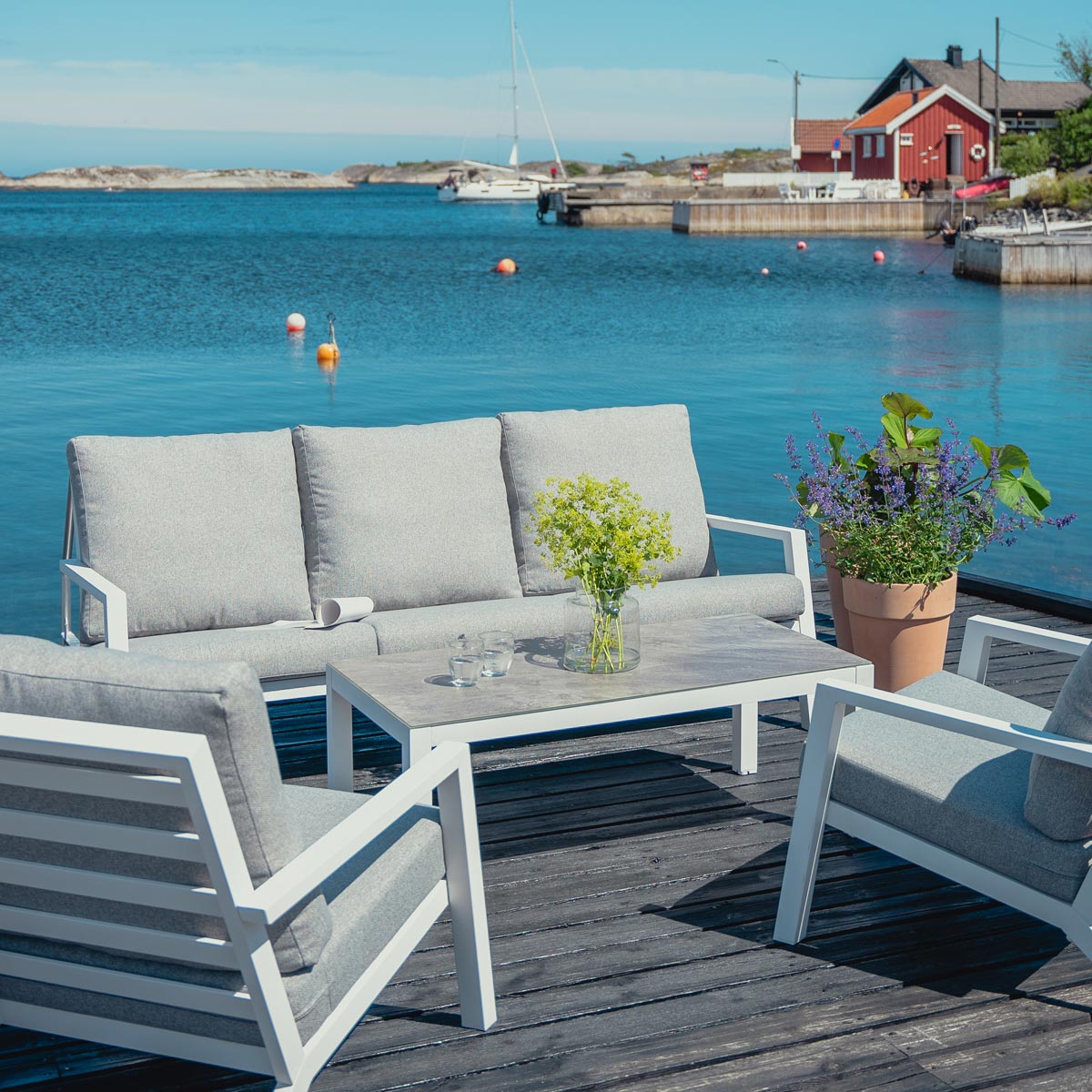 Lindøy sofabord i hvit aluminium med tilhørende sofa og stoler.