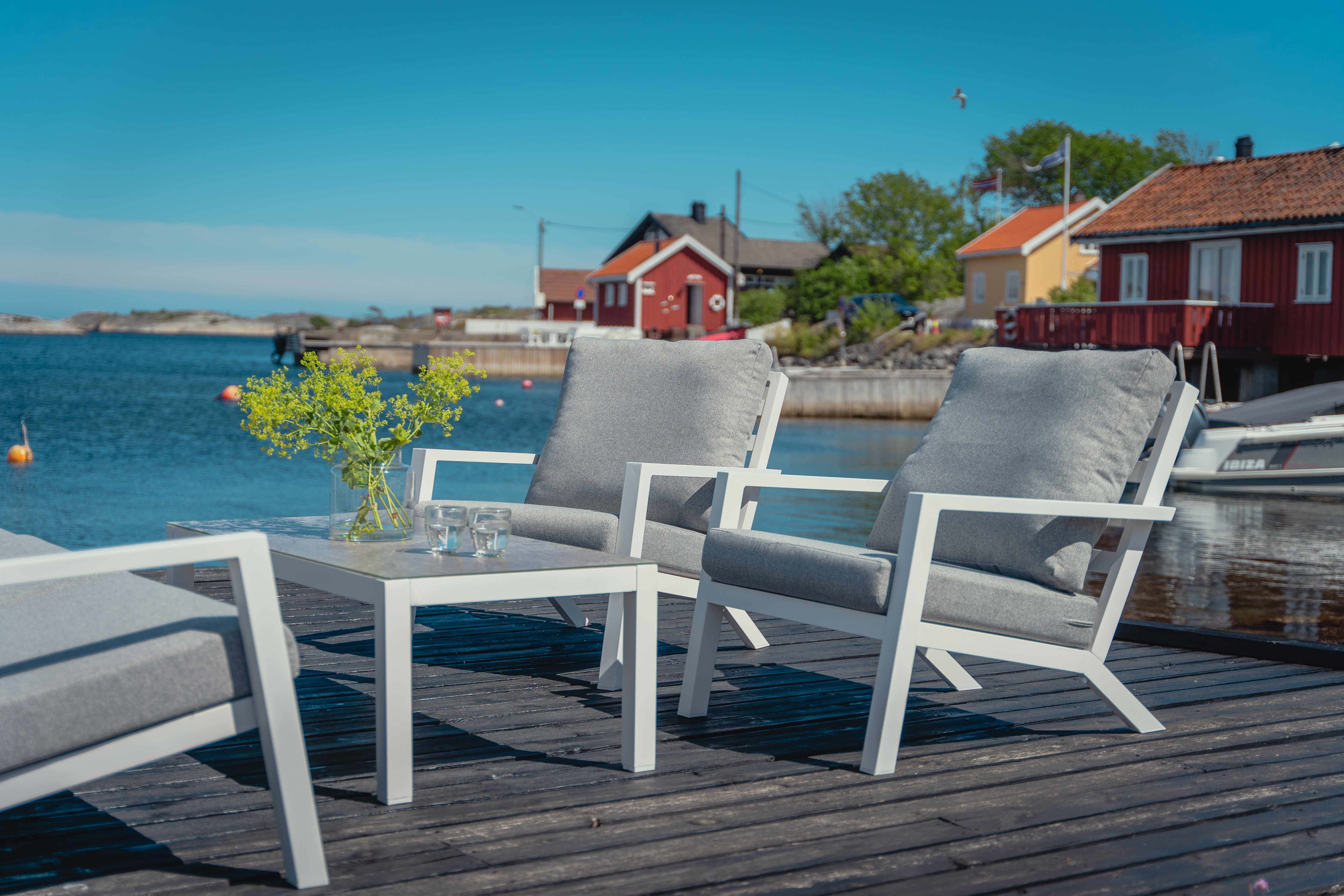 Lindøy sofabord i hvit aluminium med tilhørende sofa og stoler.
