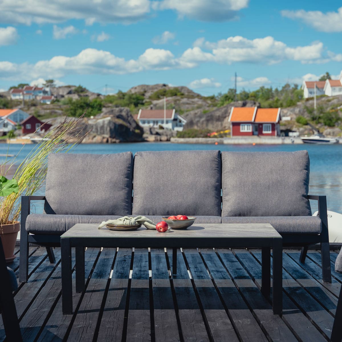Lindøy 3-seter sofa med grå puter i olefinstoff som er svært hurtigtørkende.