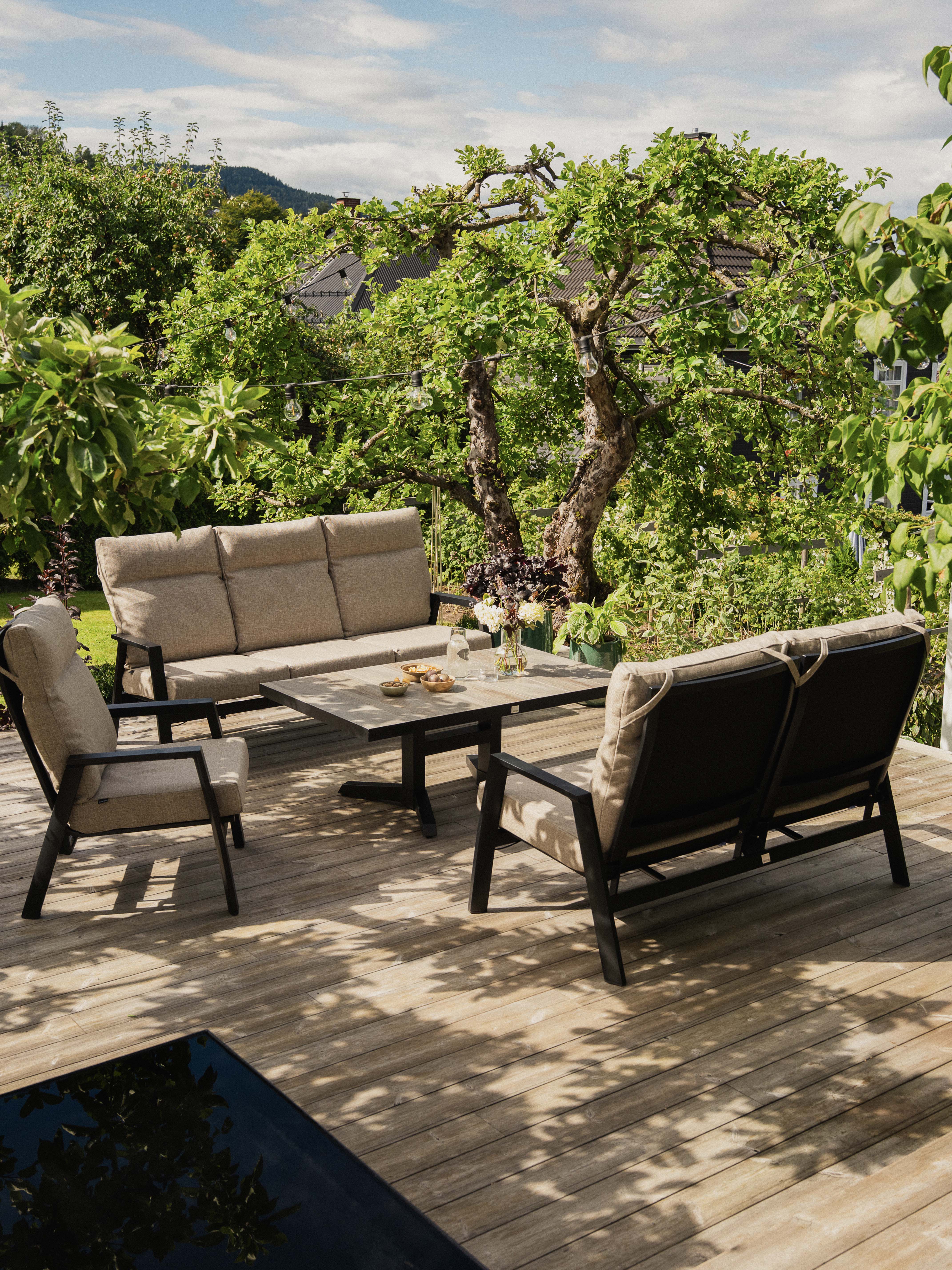 Sofagruppe i værbestandig olefin tekstil. Komfortable beige puter.