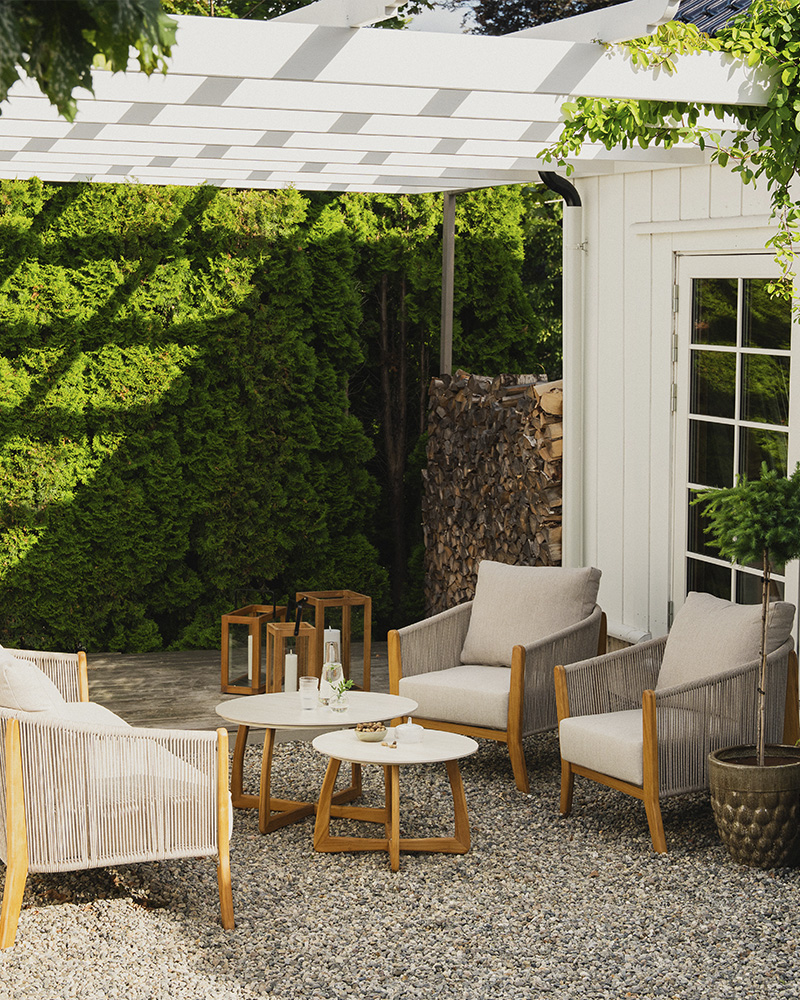 Hagemøbler i lys farge, med kofortable beige puter. Tre-detaljer