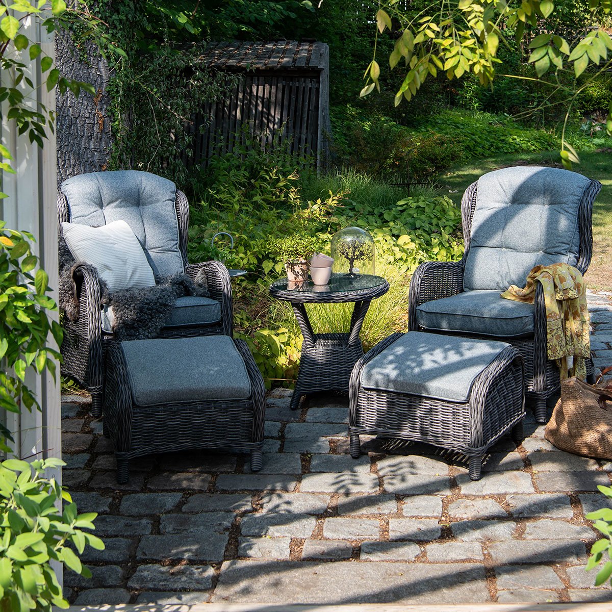 Hagestoler med fotpaller Haslev i gråfarget kunstrotting med sidebord i solfylt hage