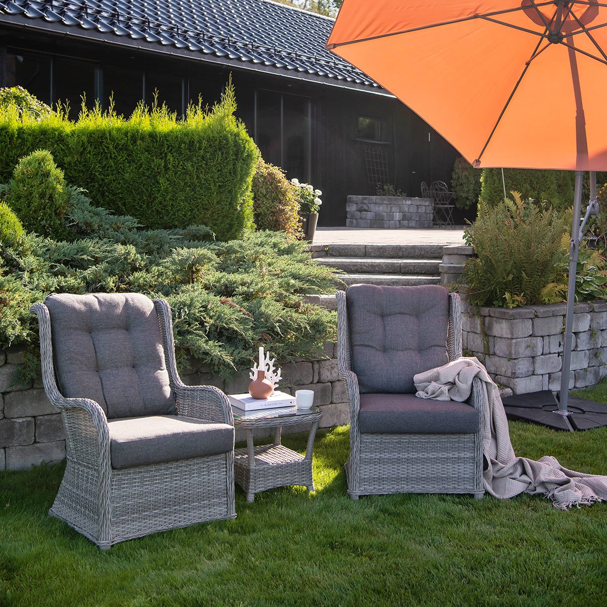 2 gode stoler med høy rygg i gråfarget kunstrotting og med puter i olefinstoff, som har som har høy lys- og fargeekthet og som tørker fort.