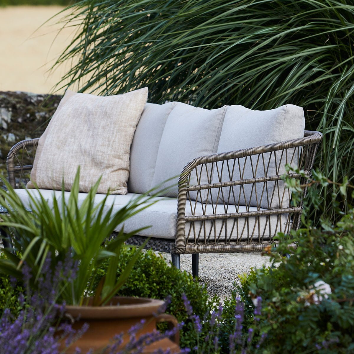 Nydelig 3 seters sofa i naturfarget kunstrotting. fletten på kunstrottingen og de lyse putene gir et romantisk, stramt utrykk