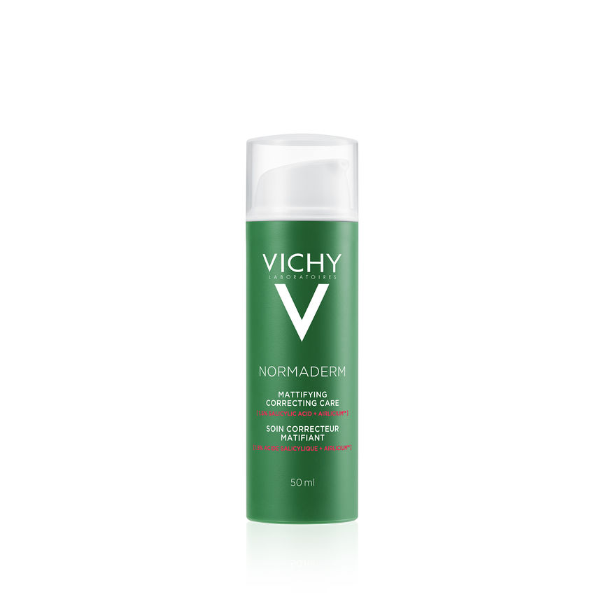 Et produktbilde av Vichy Normaderm Mattifying Correcting Care, en mattende ansiktskrem for fet og uren hud. Flasken er grønn med hvit tekst og gjennomsiktig lokk, og inneholder 50 ml. Kremen inneholder salisylsyre og AirLicium™-teknologi for å kontrollere talgproduksjonen og redusere synligheten av urenheter.