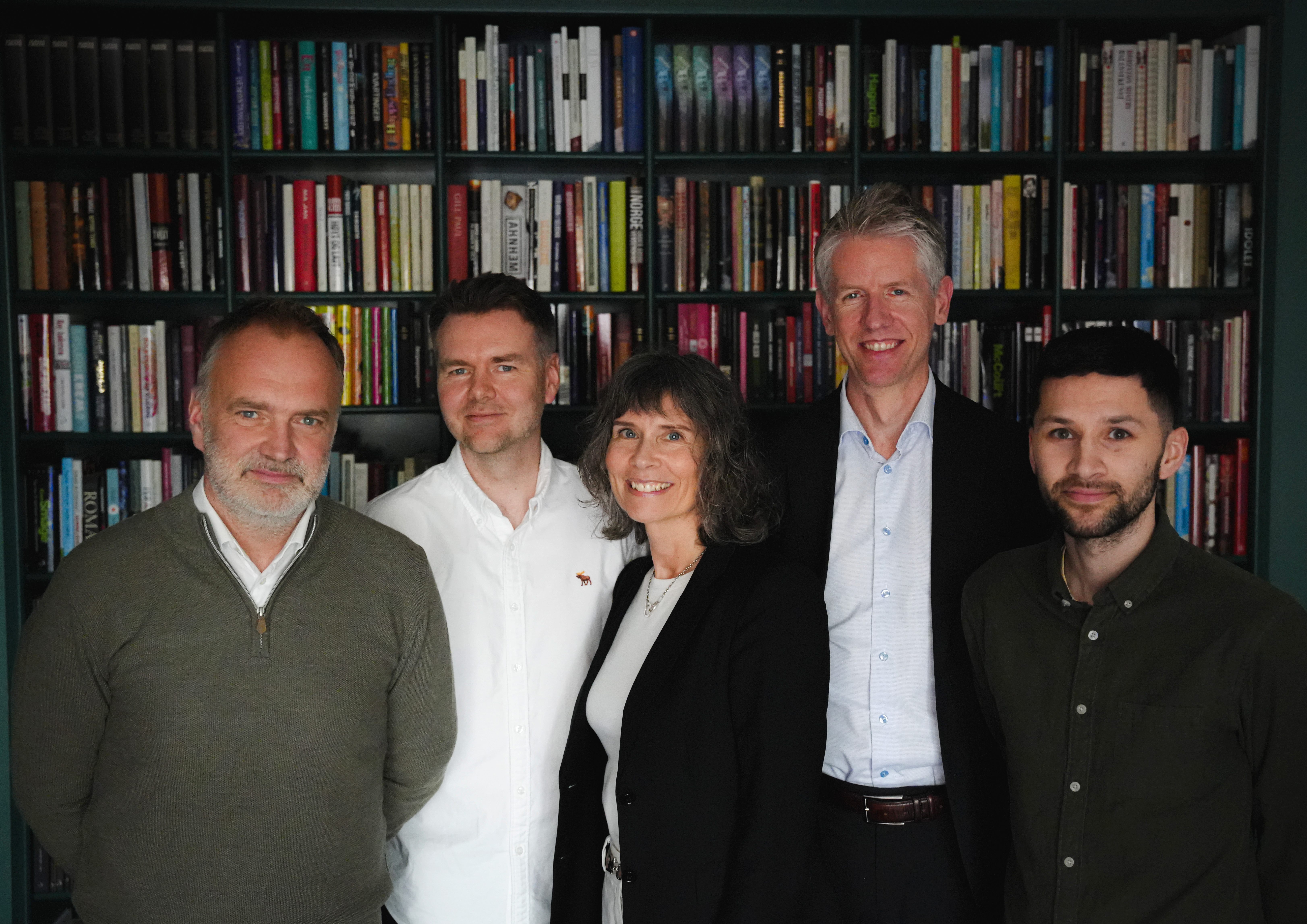 Forfatterne av forvaltningsloven står foran en stor bokhylle.