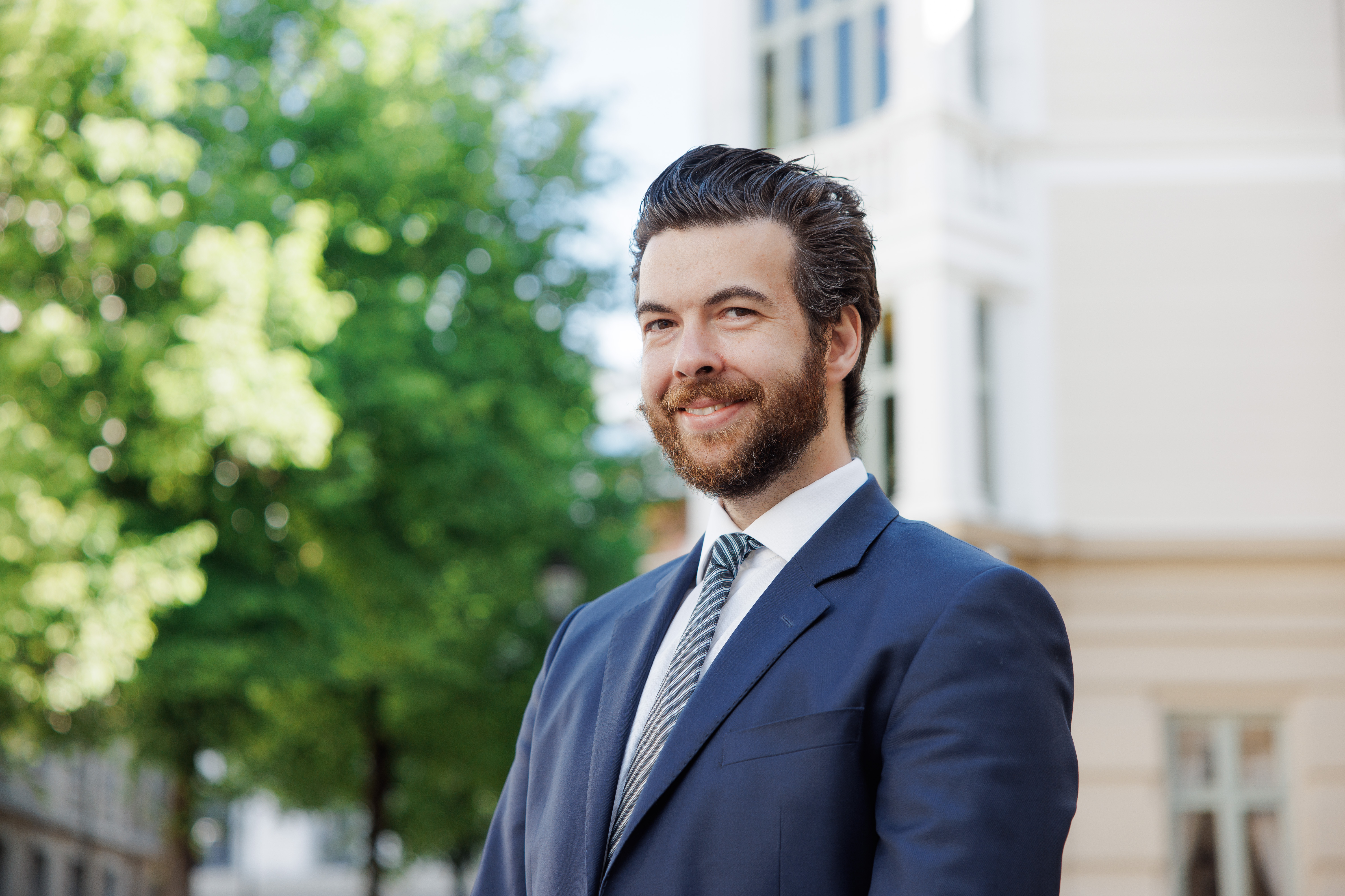 En mann i dress som smiler til kamera