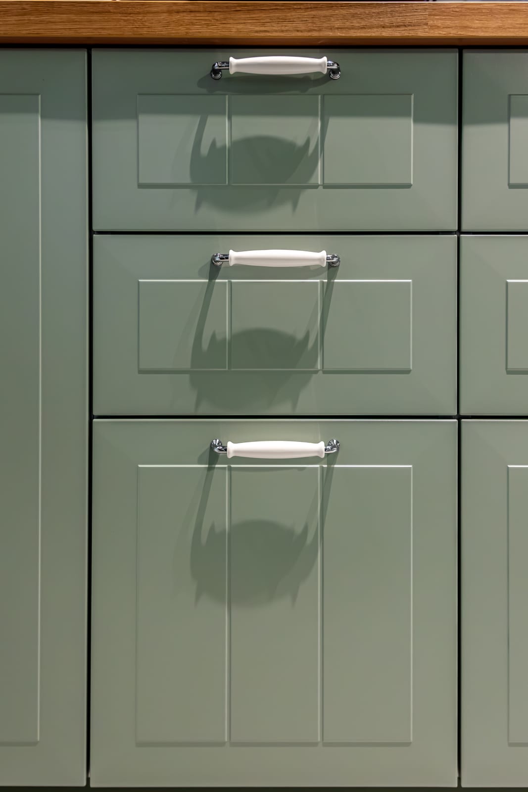 Sage green panelled drawers with metal handles.