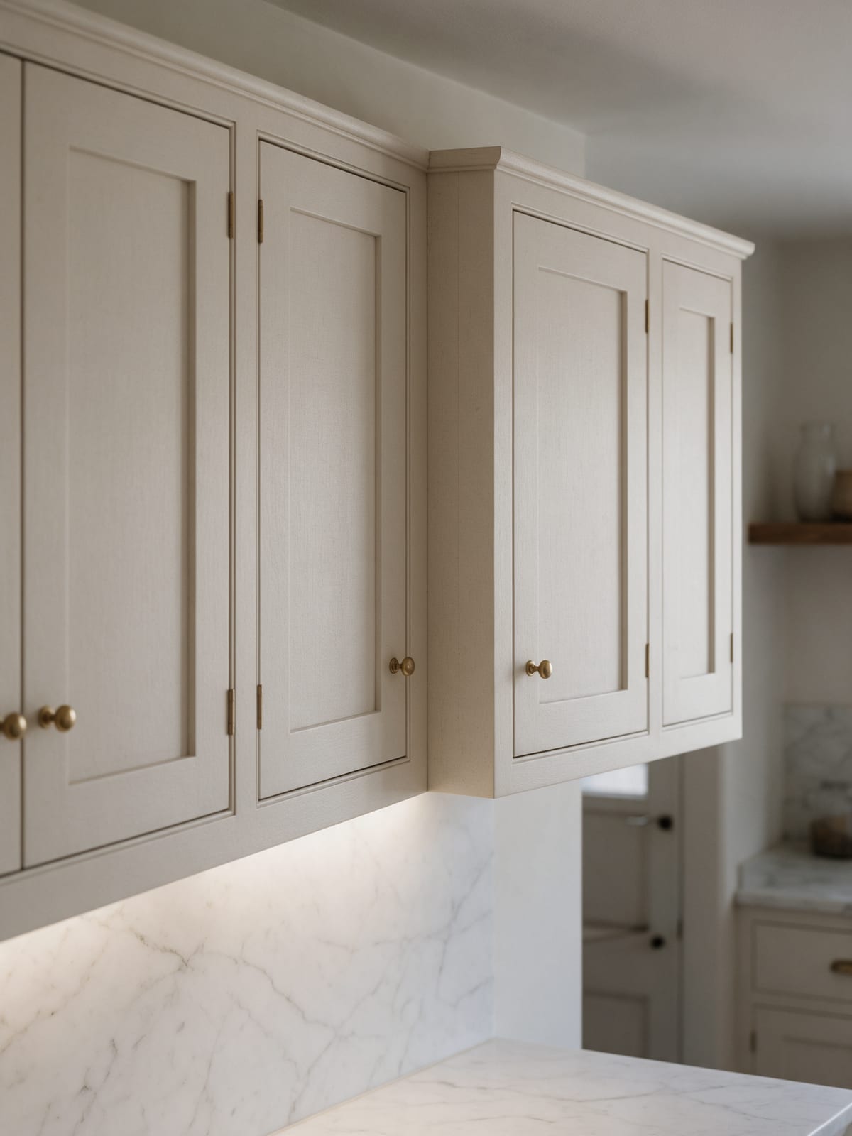Framed wall cabinets meeting in a corner, with light washing the marble below.