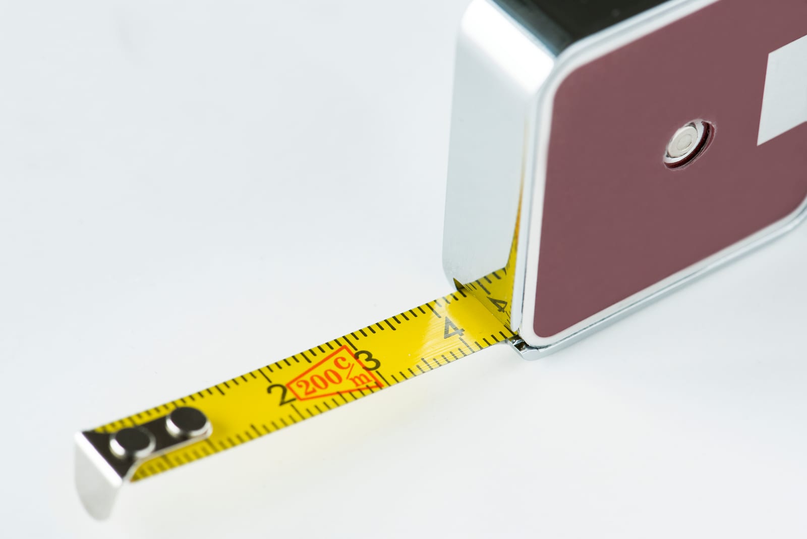 A tape measure pulled out against a white wall.