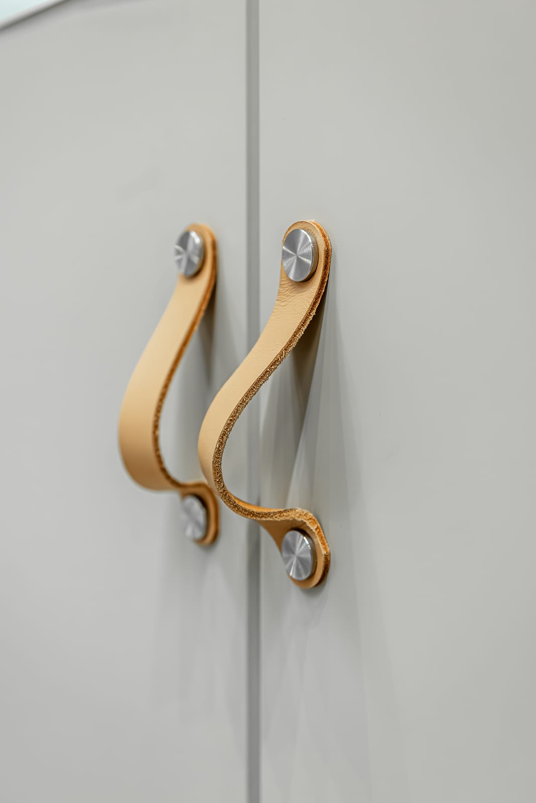Matte pale grey doors with leather pull handles.