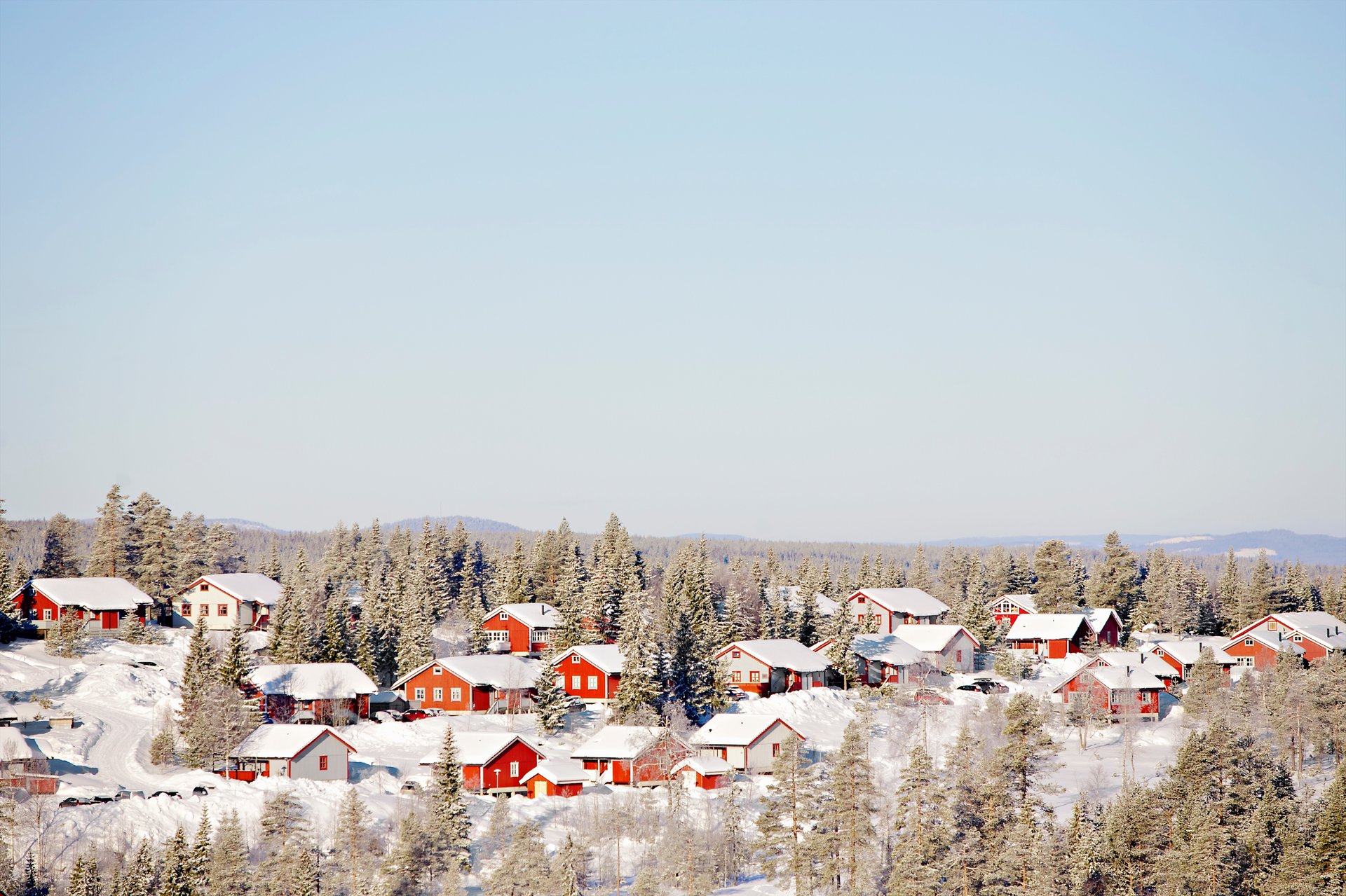 Vy över ett snötäckt landskap med röda hus. Mitsubishi Electrics luftvärmepumpar är anpassade för nordiska förhållanden och är de enda på marknaden som ger god värme inomhus även vid mycket kallt väder, tack vare Hyper Heating. Under varma sommardagar kan DOJO automatiskt kyla ner din bostad till önskad temperatur.