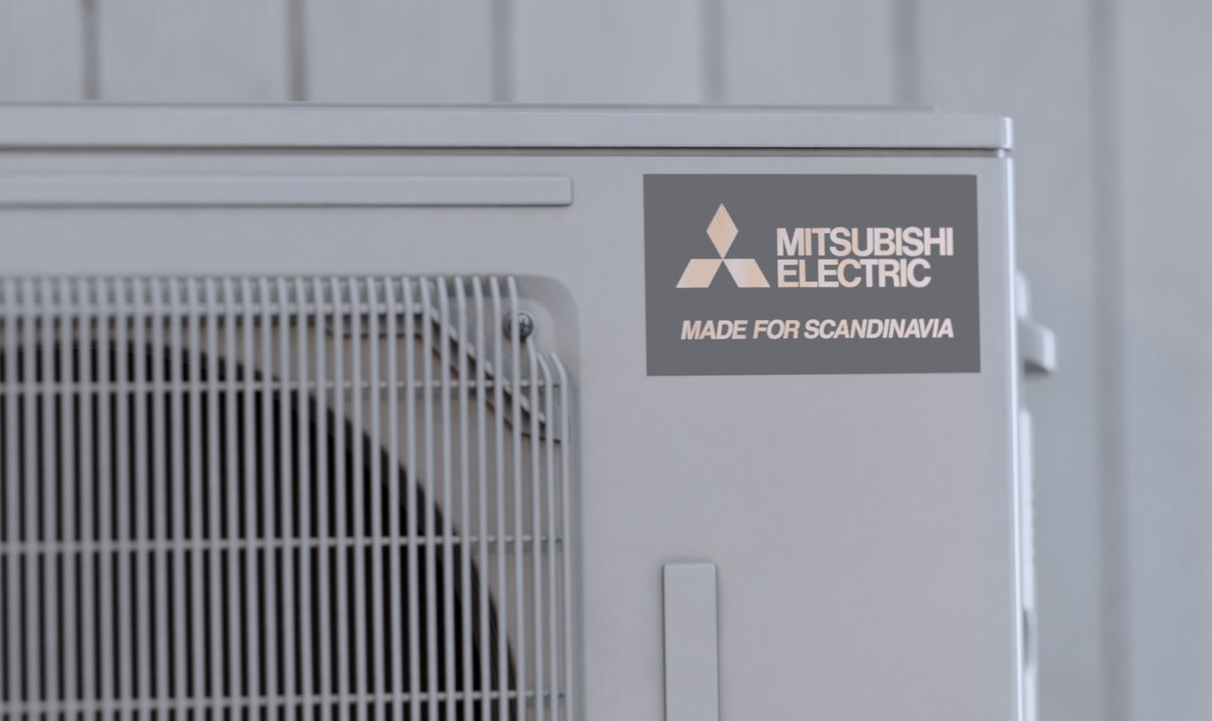 Mitsubishi Electrics utomhusenhet med märkningen Made for Scandinavia, som betonar hållbarhet och effektivitet designad för tuffa nordiska förhållanden. Enheten är monterad mot en ljus vägg och illustrerar ett engagemang för hållbara värmelösningar.