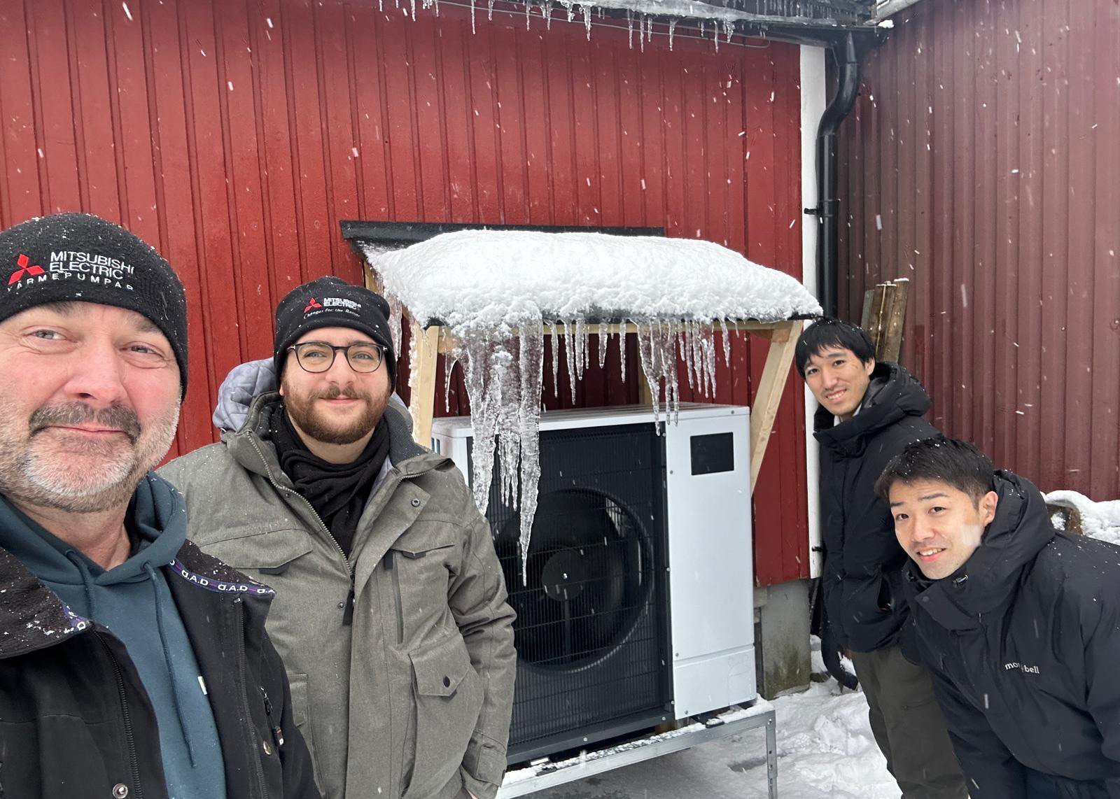 Kollegor från Mitsubishi Electric samlas framför en värmepump som testa i Norrland för att kunna märkas med Made for Scandinavia.  