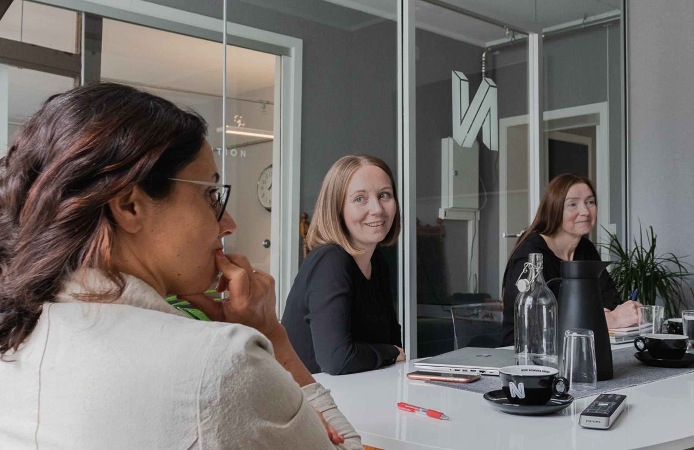 Three colleagues laughing and working together around a table — the kind of energy that builds great companies.