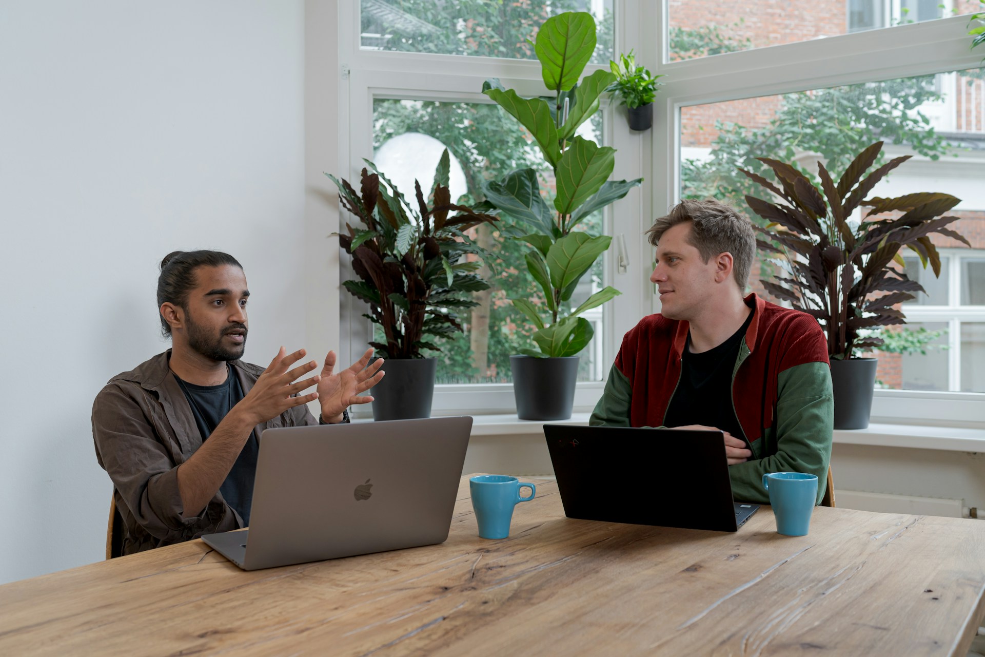 Man talking to another man in front of laptops