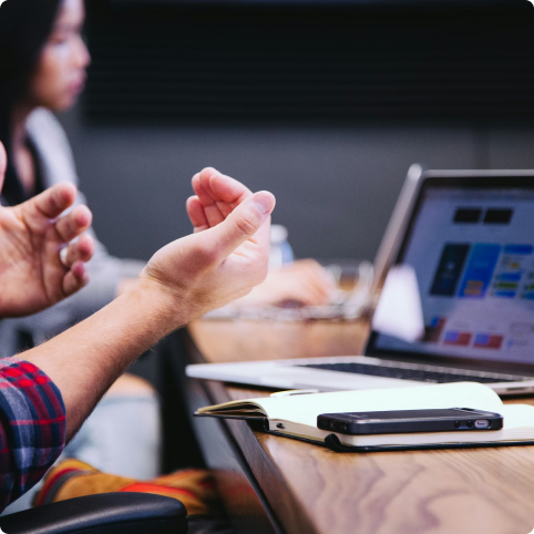 Close-up of colleagues' hands gesturing in discussion around a laptop