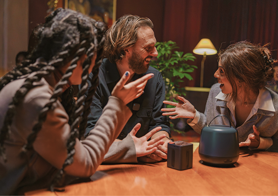 People talking together eagerly around a table with the Sound Capsule next to them