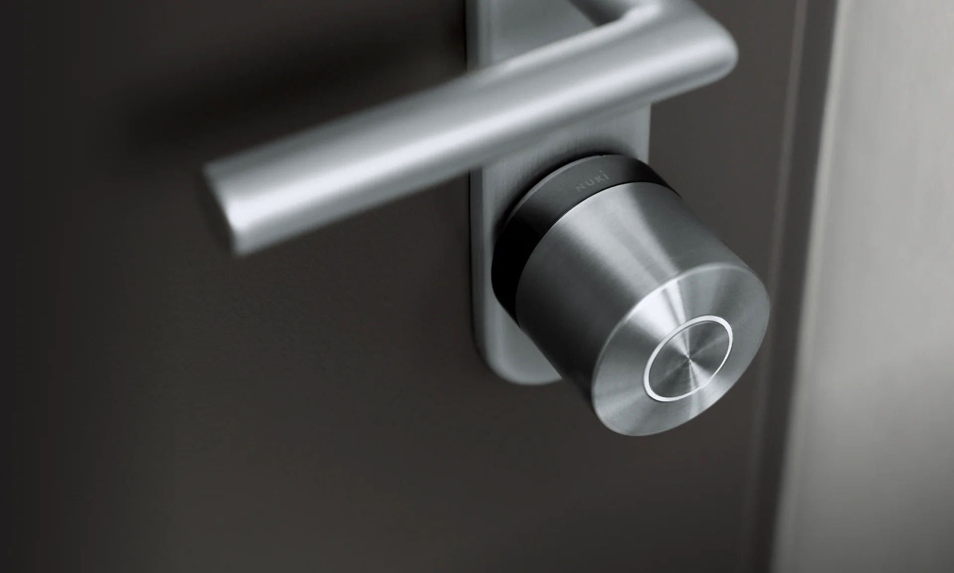 Close-up of Nuki Smart Lock Ultra in silver, mounted on a dark door.